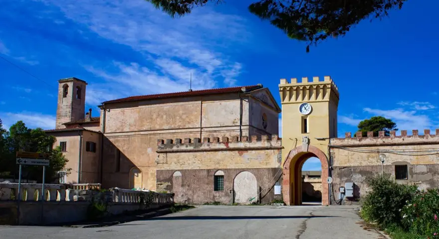 Antico borgo sull'isola di Pianosa, con torre dell'orologio e campanile sotto un cielo azzurro.