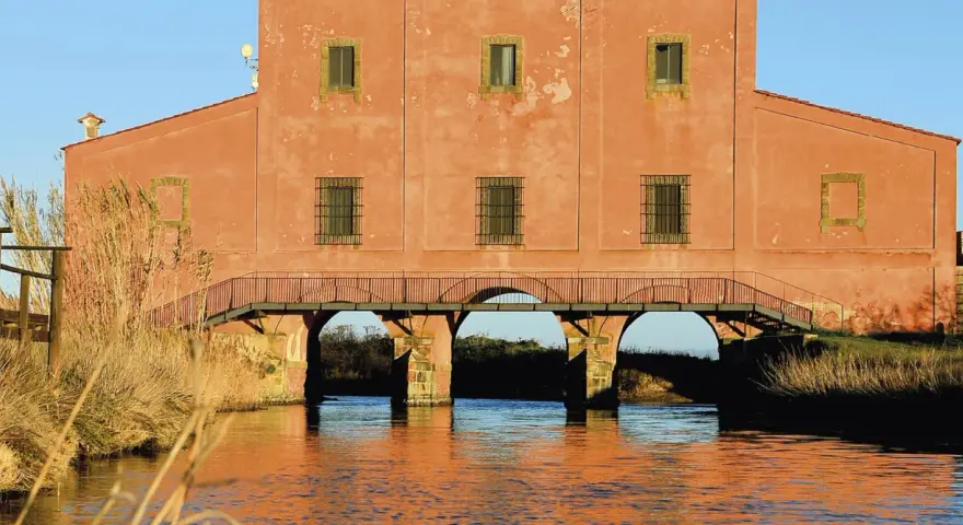Edificio storico con ponticello ad archi sull'acqua, un'idea di cosa vedere vicino a Castiglione della Pescaia.