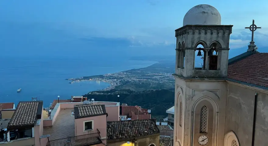 Castelmola cosa vedere: vista panoramica sul mare e sulla costa siciliana, con un campanile in primo piano.