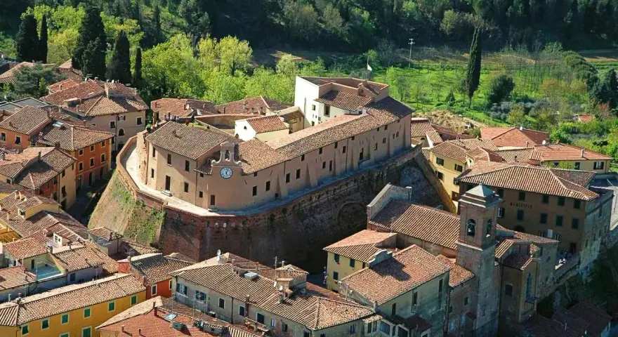 Borgo fortificato con case in pietra e tetti rossi, un campanile e un orologio. Un'ottima meta per scoprire cosa vedere vicino Pisa.
