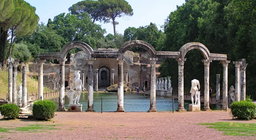 Resti archeologici di Villa Adriana con statue classiche e un laghetto, immersi nel verde.