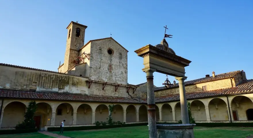 Cortile con pozzo e campanile di Castel Nuovo Berardenga, sotto un cielo azzurro.
