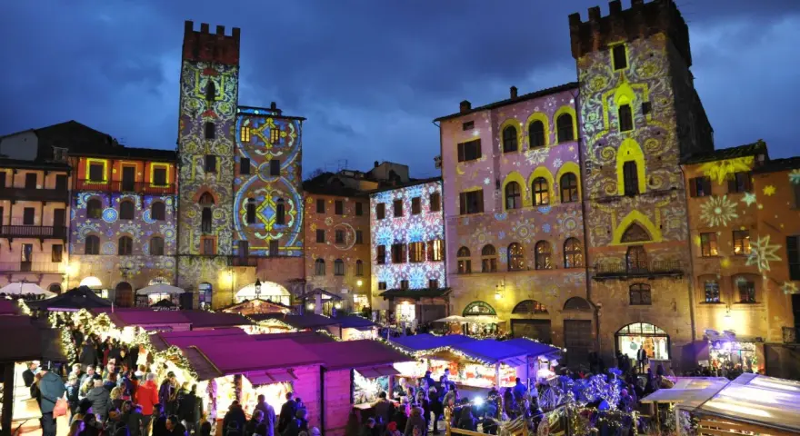 Mercatino natalizio ad Arezzo, con palazzi illuminati da proiezioni colorate. Vale la pena visitare Arezzo per questa magica atmosfera.