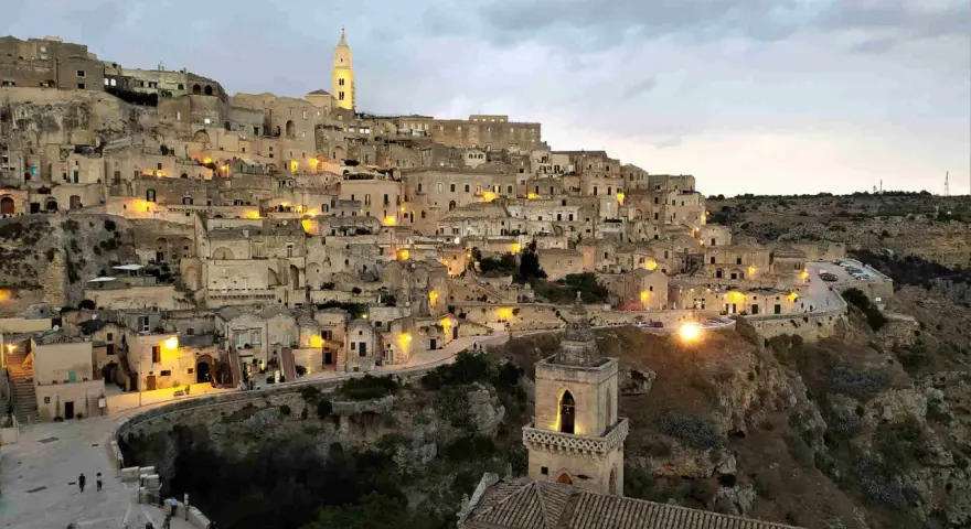 I Sassi di Matera illuminati al crepuscolo, un panorama mozzafiato di case scavate nella roccia e chiese antiche.