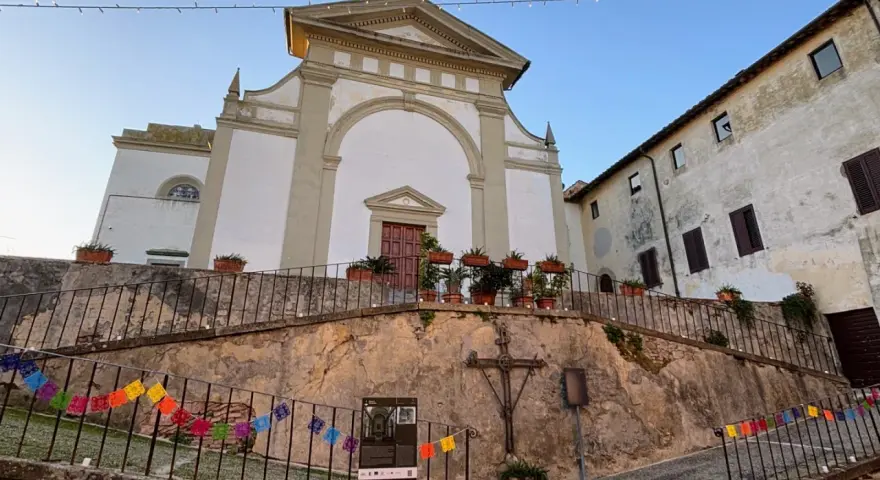 Terricciola cosa vedere: la chiesa parrocchiale domina la piazza, con un'antica croce e festoni colorati che creano un'atmosfera suggestiva.