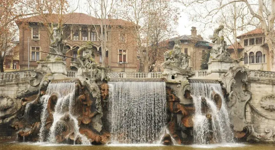 Fontana monumentale nel Parco del Valentino, con statue e cascate d'acqua che scendono su rocce scultoree.