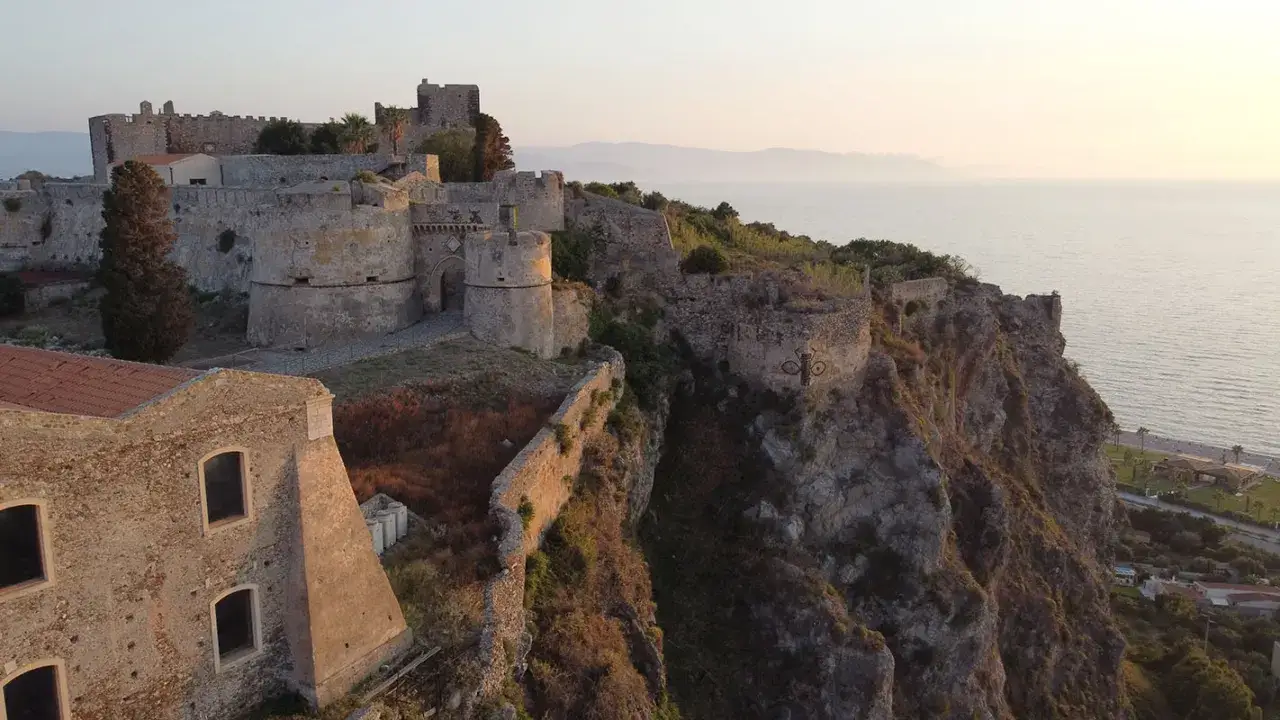 Il complesso monumentale del castello di Milazzo domina la costa rocciosa al tramonto.