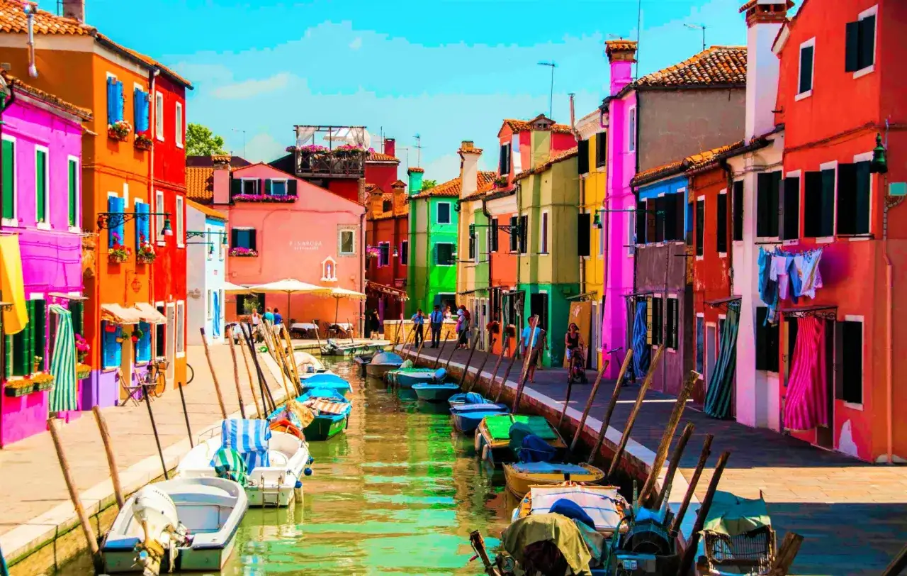 Coloratissime case a Burano, una delle isole da visitare a Venezia, con barche ormeggiate lungo il canale.