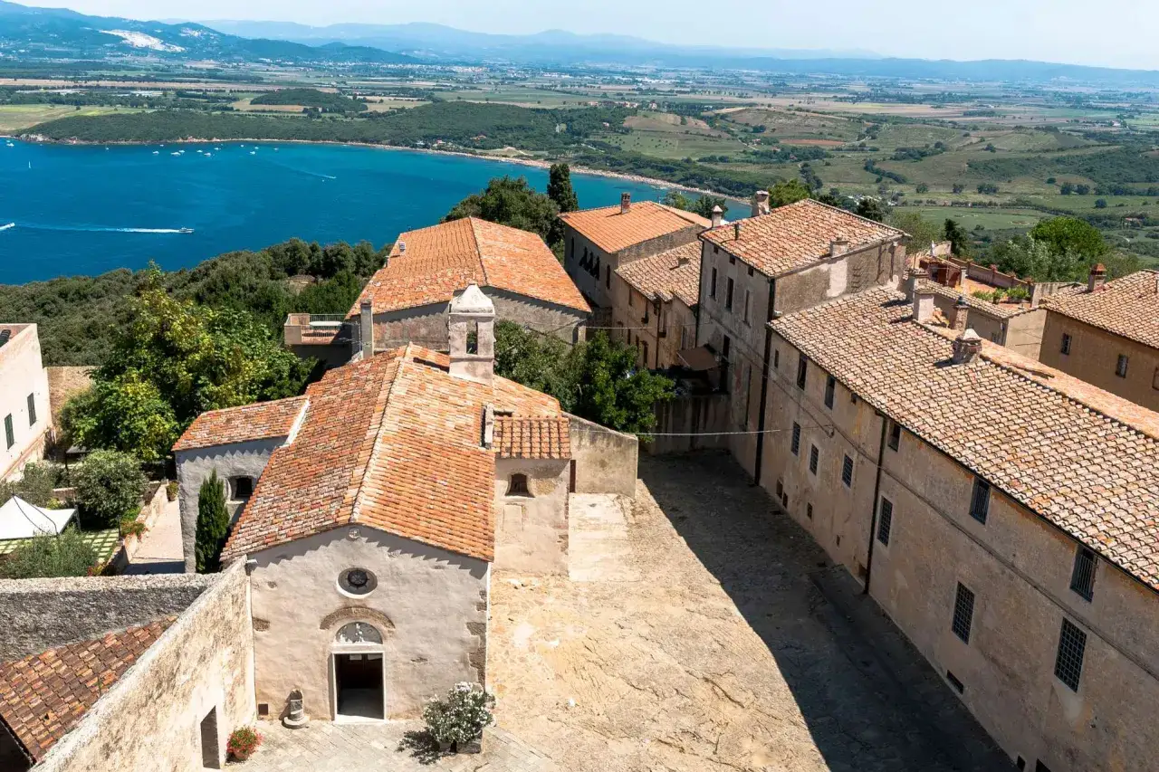 Antico borgo di Populonia centro storico, con case in pietra e tetti rossi affacciate sul mare blu.