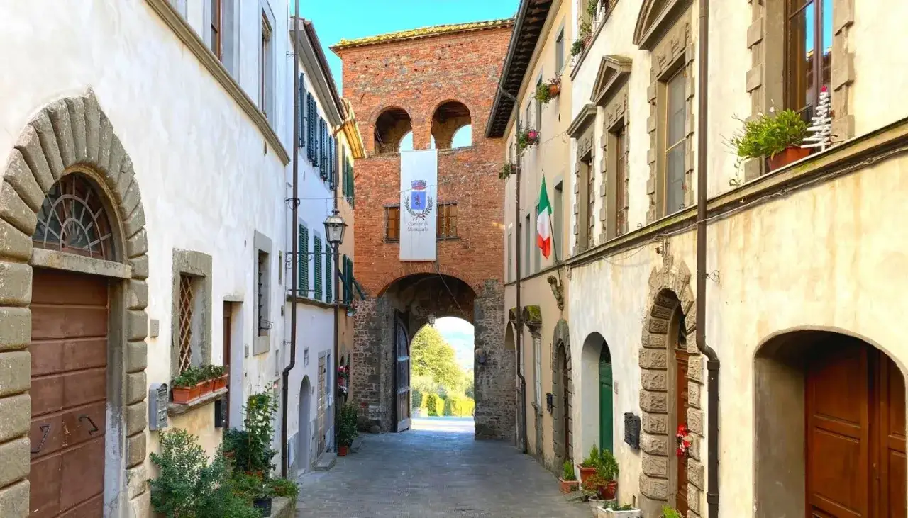 Un vicolo nel montecarlo centro storico, con un arco in mattoni e un vessillo comunale.
