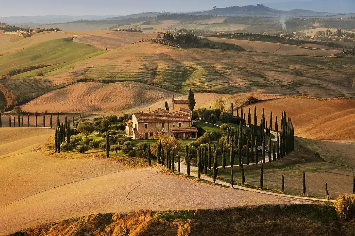 Colline toscane con cipressi e un casale, un'immagine iconica di cosa vedere a Montalcino.