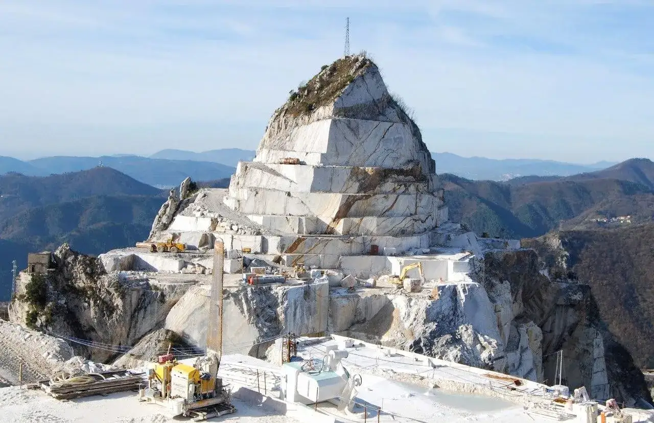 Cave di marmo a Carrara, un paesaggio unico da scoprire. Macchinari estraggono il prezioso materiale dalle montagne.