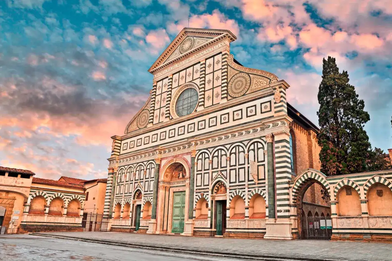 La facciata rinascimentale della basilique Santa Maria Novella a Firenze, con il suo cielo colorato al tramonto.