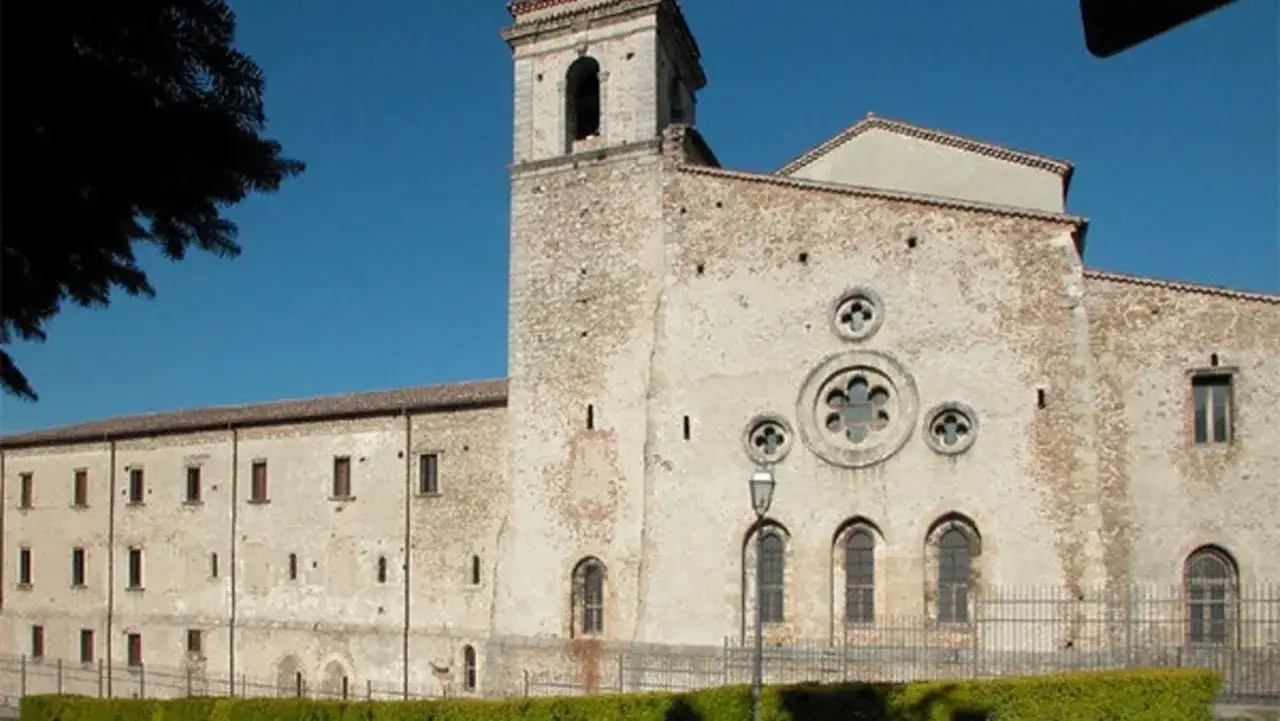 Antica abbazia di San Giovanni in Fiore, con campanile e finestre gotiche, sotto un cielo azzurro.