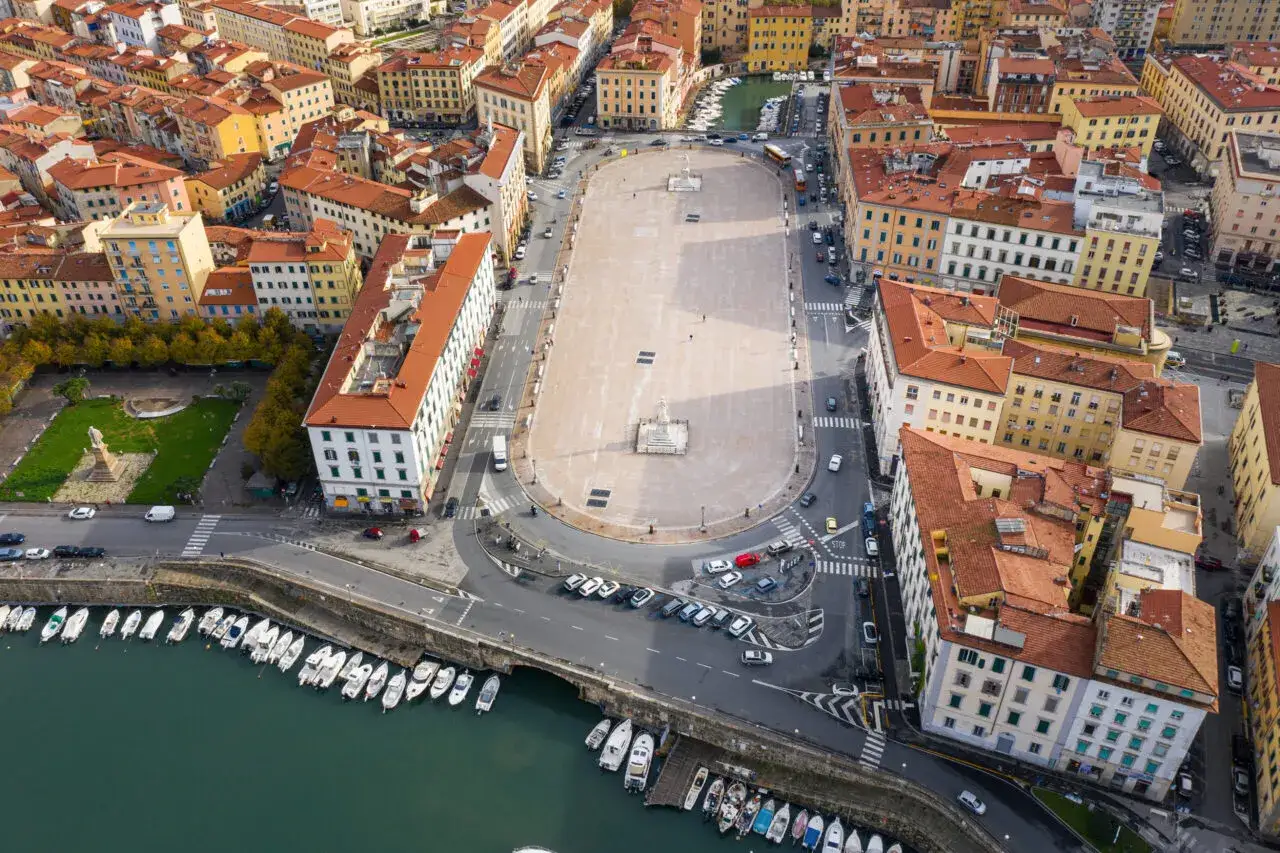 Vista aerea della Piazza della Repubblica a Livorno, con il porto e le case dai tetti rossi.