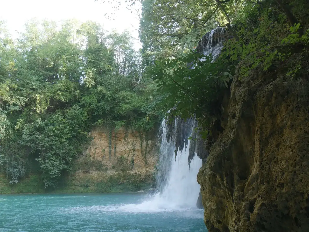 Cascata sul fiume Colle Val d'Elsa, con rocce calcaree e vegetazione lussureggiante.