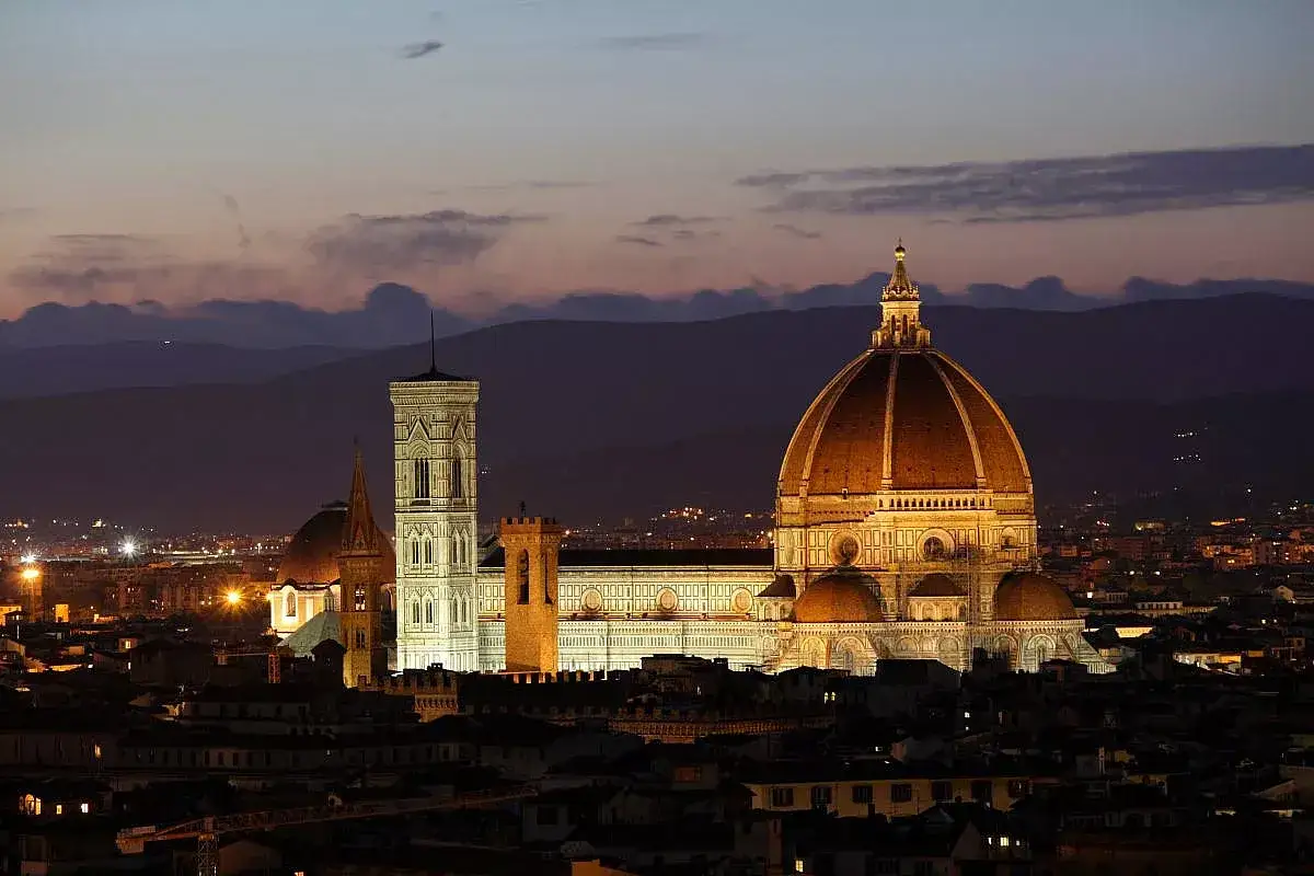 Firenze illuminata al tramonto vista da Piazzale Michelangelo: il Duomo e il Campanile di Giotto risplendono contro le colline.