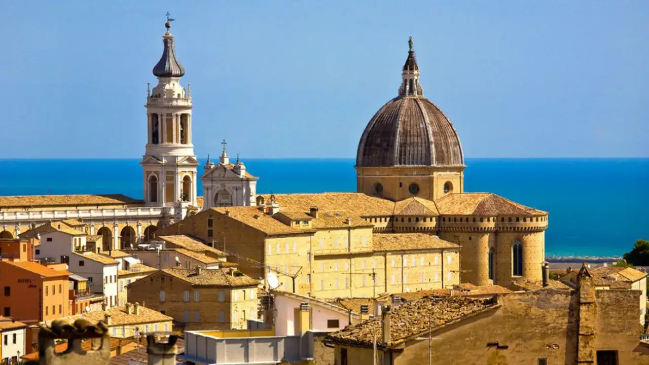 La Basilica della Madonna di Loreto domina il paesaggio con la sua cupola imponente e il campanile slanciato, affacciata sul blu del mare Adriatico.