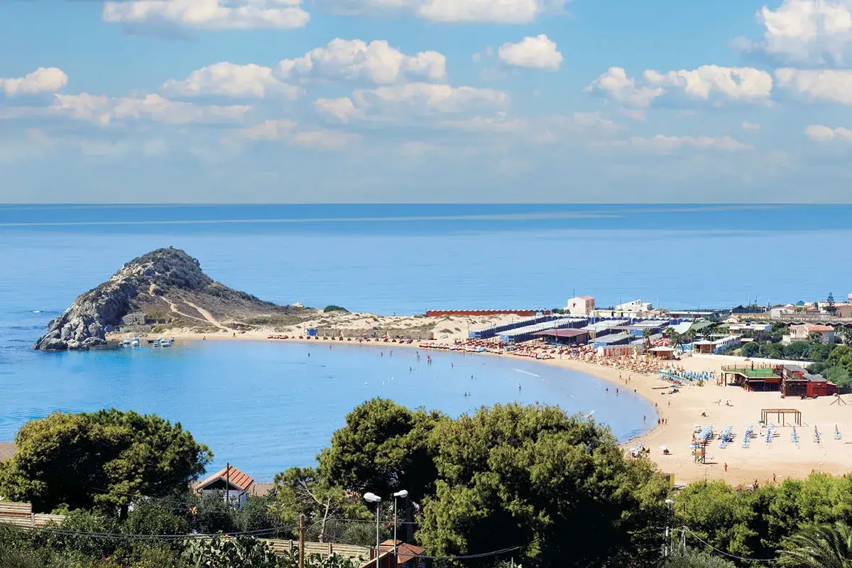 Spiaggia di Licata, cosa vedere: un'isola rocciosa con barche, una baia con stabilimenti balneari e gente che si gode il sole.