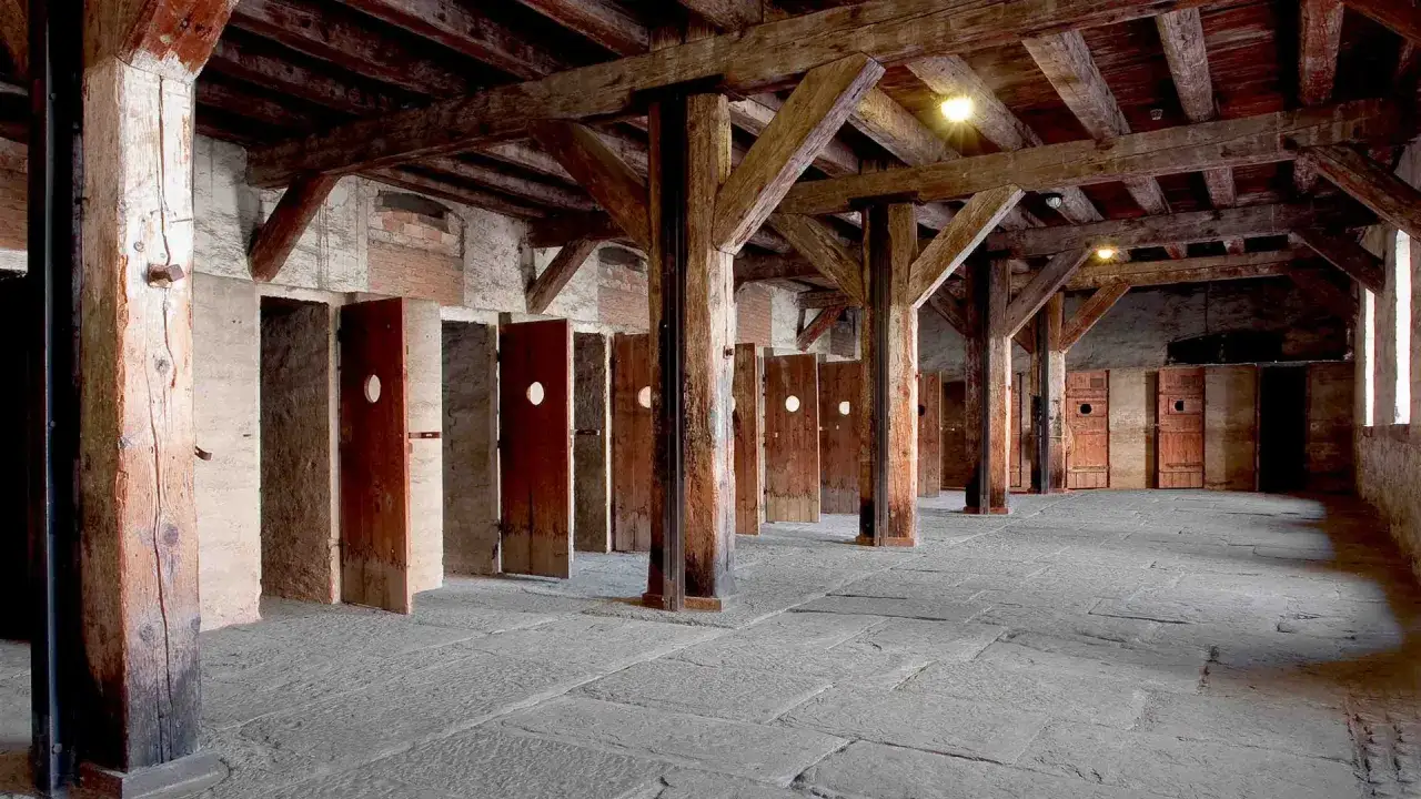 Interno della risiera di San Sabba con file di porte in legno e colonne massicce.