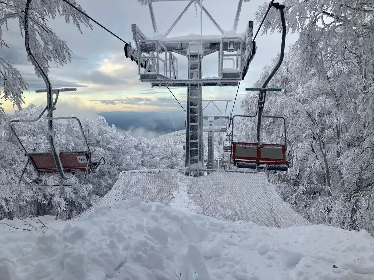 Funivia Monte Amiata innevata, con seggiovie ghiacciate e alberi coperti di brina. Paesaggio invernale suggestivo.