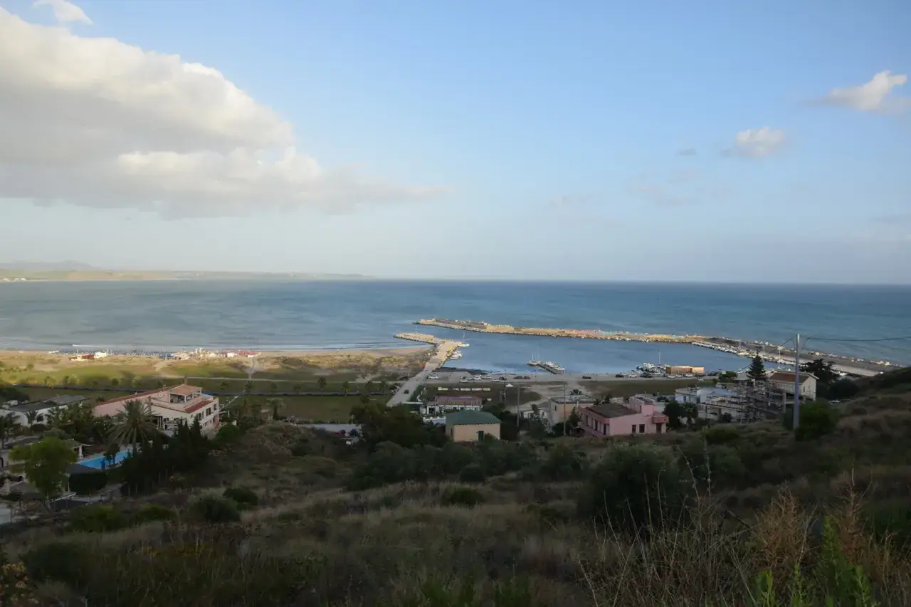 Vista panoramica del porto palo con mare azzurro, spiaggia e case colorate.