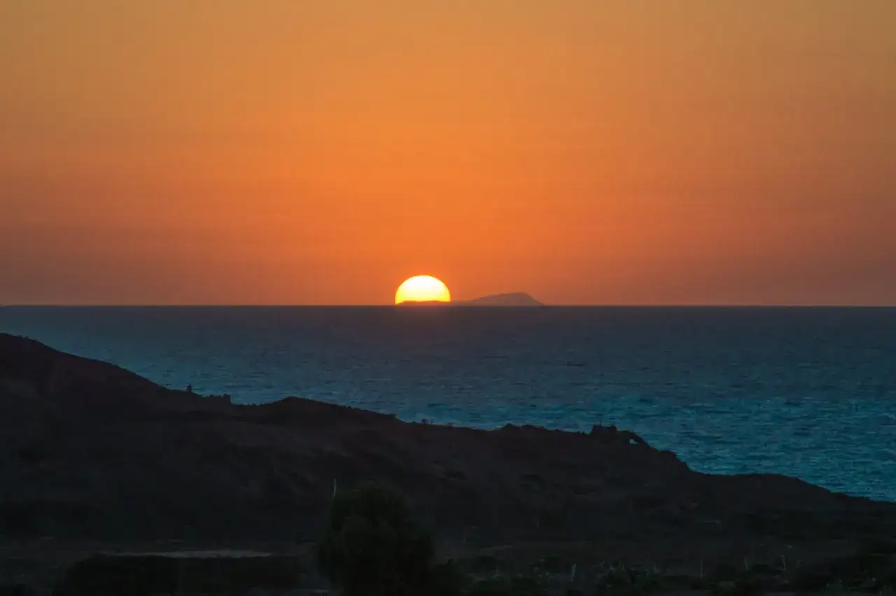 Tramonto sull'isola di Pantelleria, dove il sole cala all'orizzonte, tingendo il cielo di arancione.
