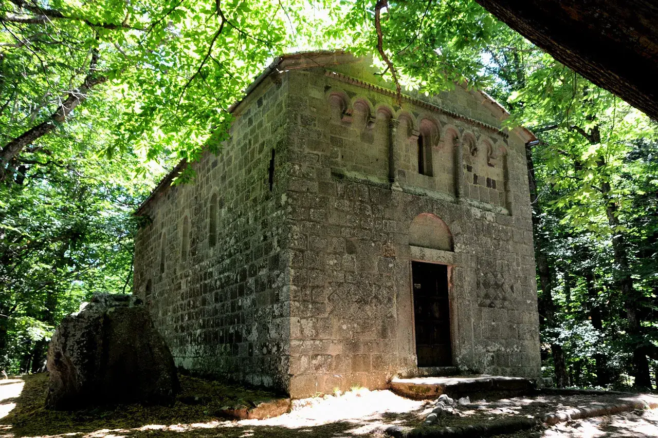 Antica pieve in pietra nel bosco Isabella, Radicofani, immersa nel verde.