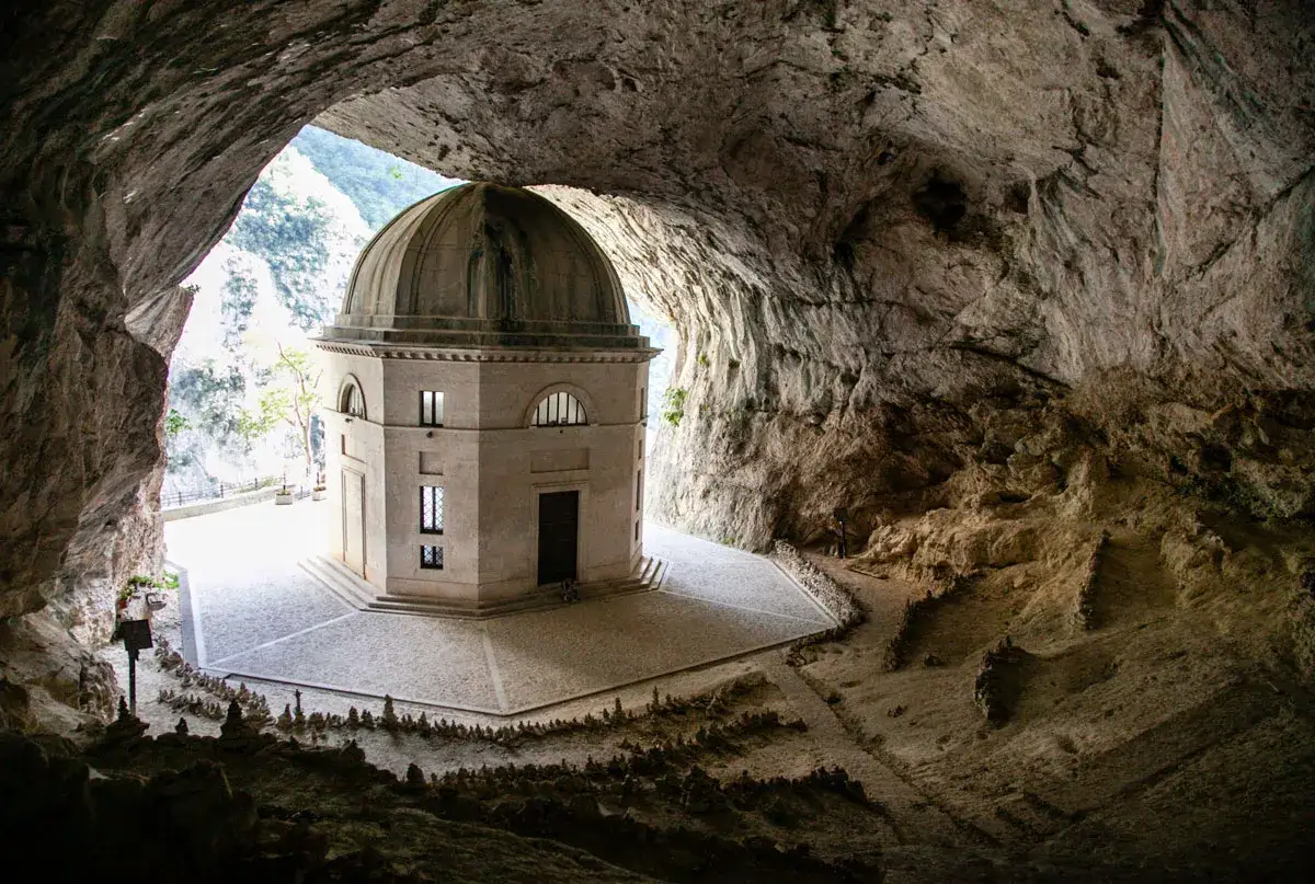 Il tempio del Valadier, un'architettura neoclassica con cupola, emerge maestoso dall'interno di una grotta naturale, con un'apertura che rivela il paesaggio esterno.