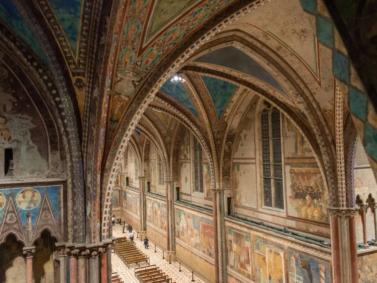Interno della Basilica San Francesco Assisi, con affreschi medievali e volte decorate.