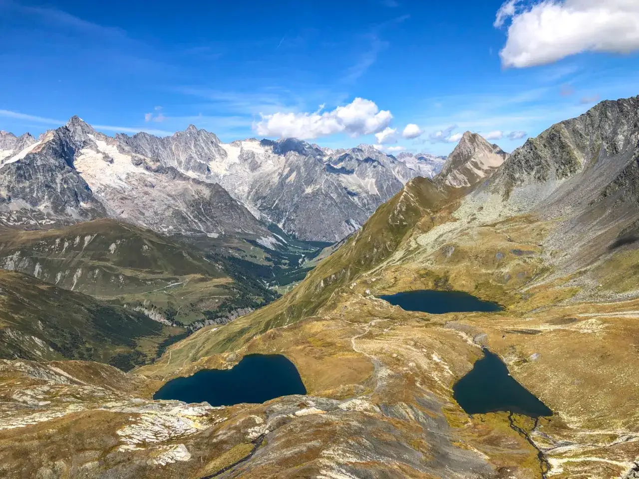 Laghi alpini riflettono il cielo azzurro tra le vette innevate del Gran San Bernardo.