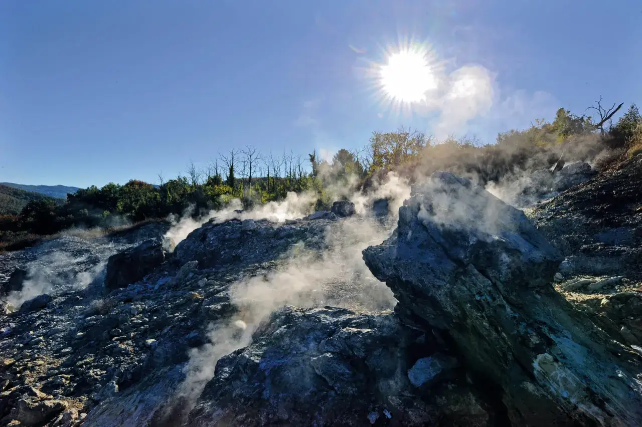 Fumarole attive nel Val di Cecina, con vapore che sale tra le rocce sotto un sole splendente.