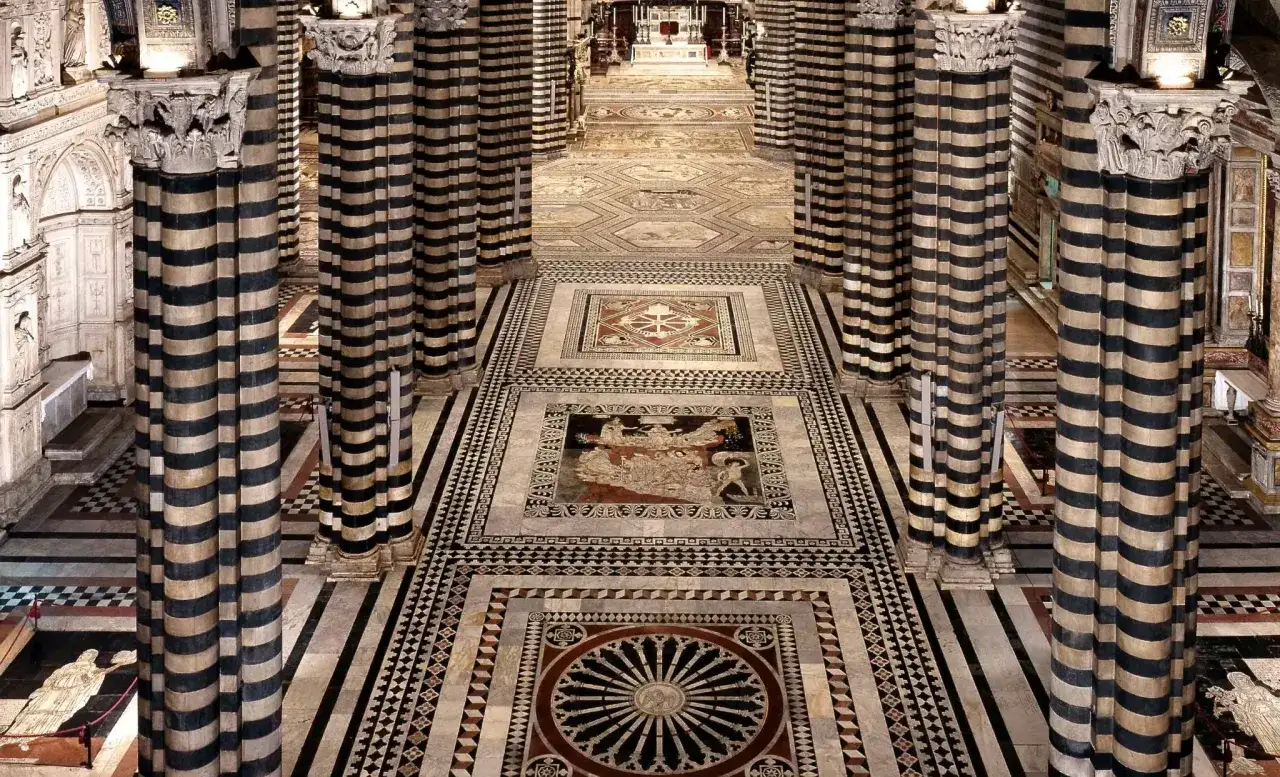 Il magnifico pavimento del Duomo di Siena, con le sue colonne a strisce e i dettagli in marmo, crea un percorso visivo mozzafiato.