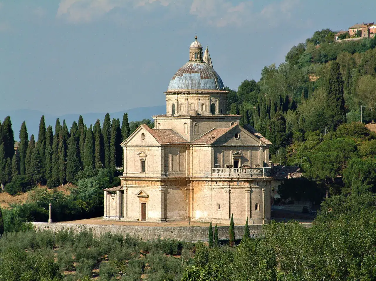 La chiesa di San Biagio a Montepulciano, con la sua imponente cupola, si erge tra cipressi e ulivi, un gioiello rinascimentale nel paesaggio toscano.