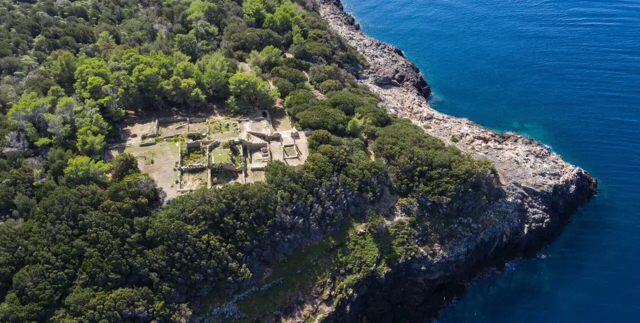 Rovine antiche sull'isola di Giannutri, immerse nel verde e bagnate dal blu intenso del mare.