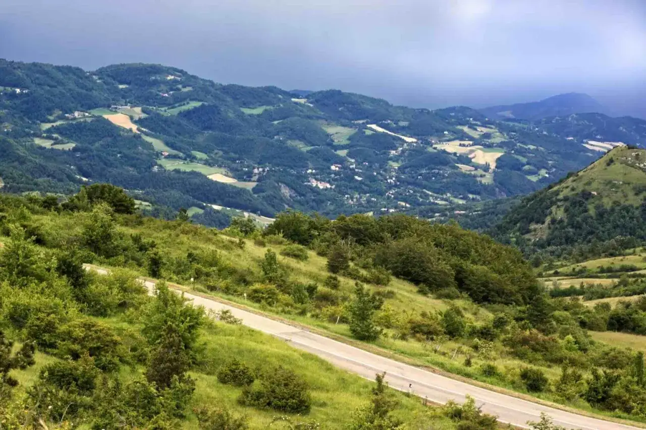 Strada panoramica che sale verso il passo della Futa, tra colline verdi e un cielo nuvoloso.