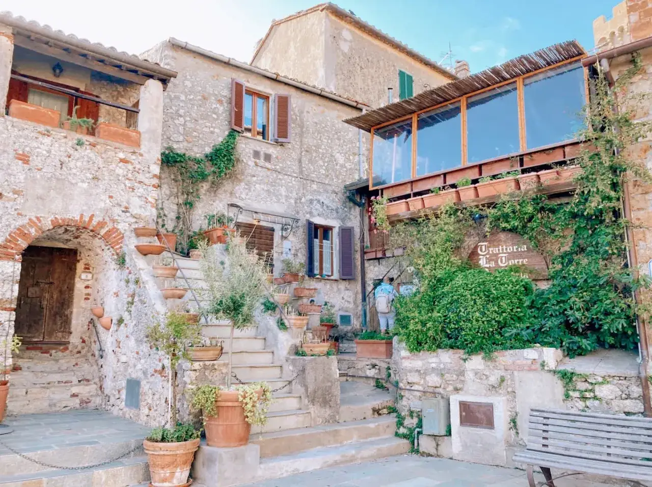 Un angolo pittoresco con scale in pietra, vasi di fiori e la trattoria