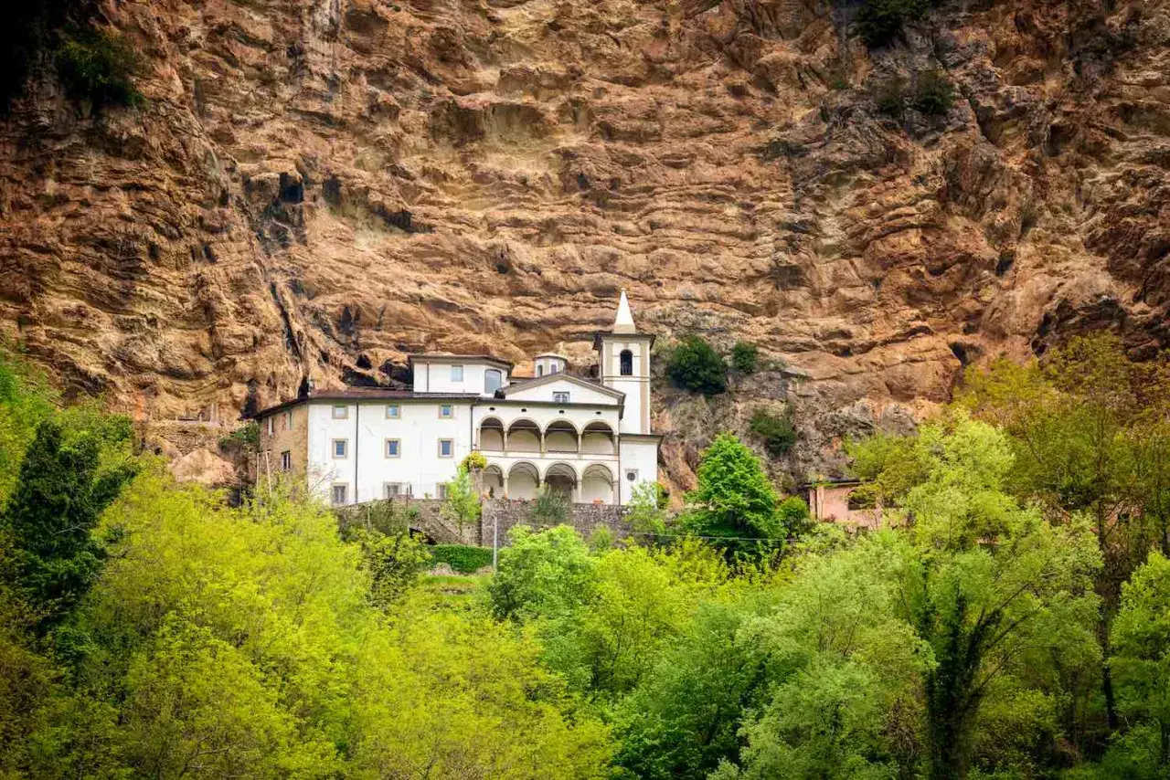 L'eremo di Calomini, un complesso monastico bianco incastonato nella roccia, circondato da un verde lussureggiante.