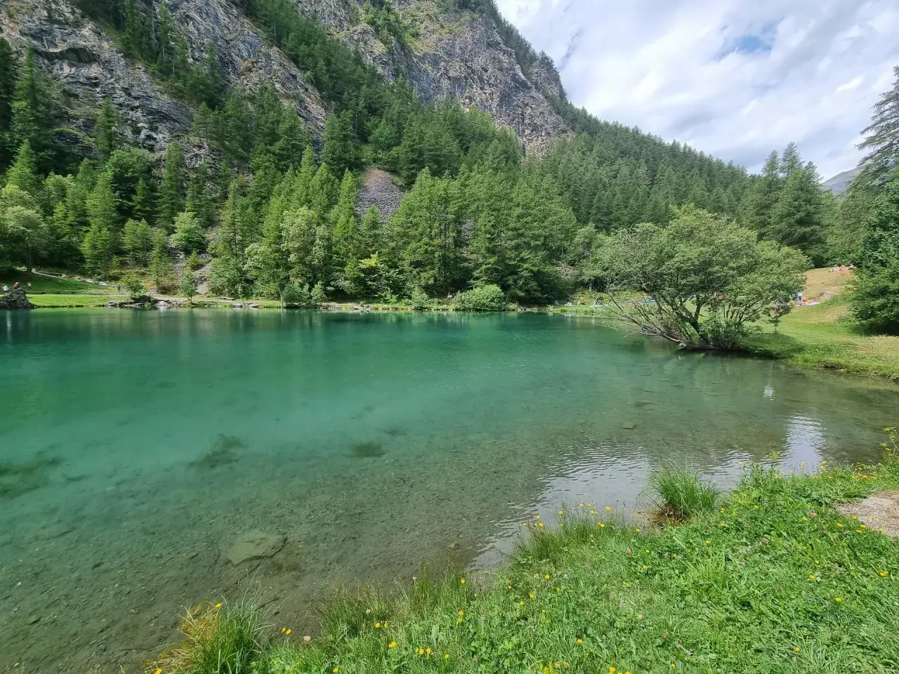 Lago alpino dalle acque cristalline nel Val di Susa, circondato da fitti boschi e imponenti pareti rocciose.