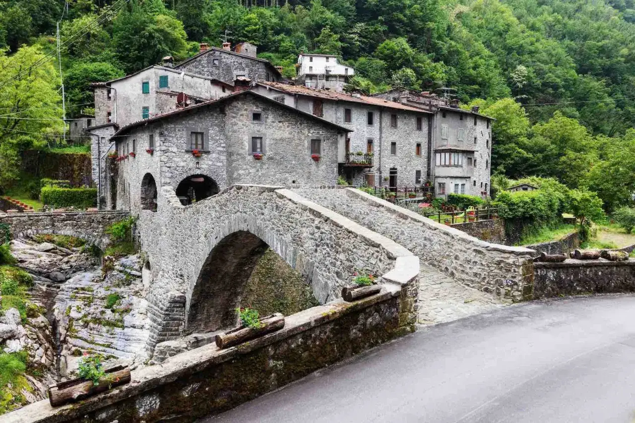 Ponte in pietra e case antiche nel borgo di Vergemoli, incastonato tra le verdi montagne.