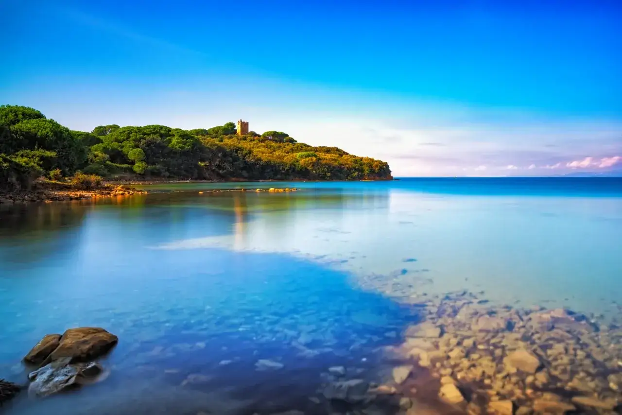 Acque cristalline e una torre antica dominano la spiaggia bianco Punta Ala. Un paesaggio da sogno.