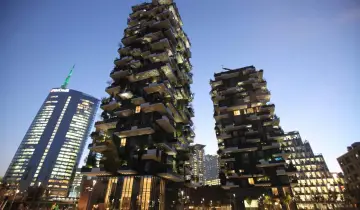 Il Bosco Verticale di Milano, con i suoi grattacieli ricoperti di alberi e piante, si staglia contro il cielo serale.
