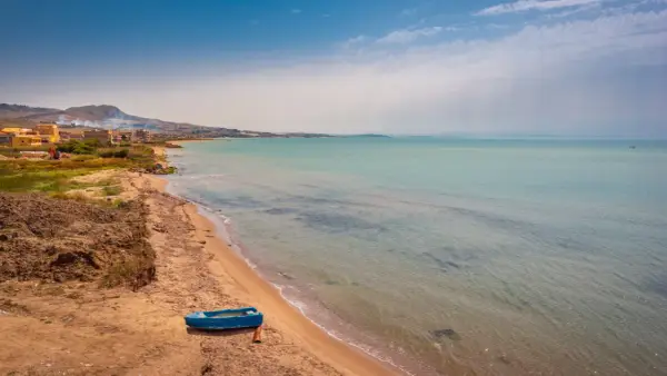Spiaggia di Licata con barca blu e mare calmo. Un paesaggio da esplorare, tra terra e acqua cristallina.