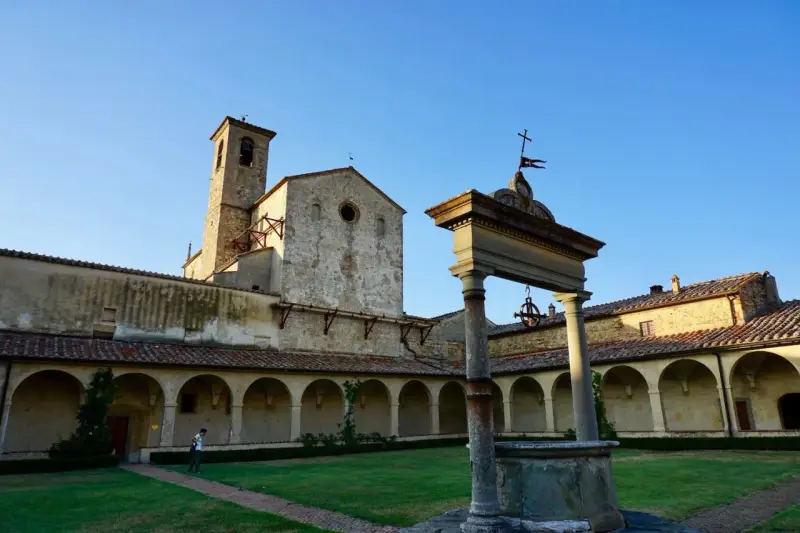 Cortile con pozzo e campanile di Castel Nuovo Berardenga, sotto un cielo azzurro.